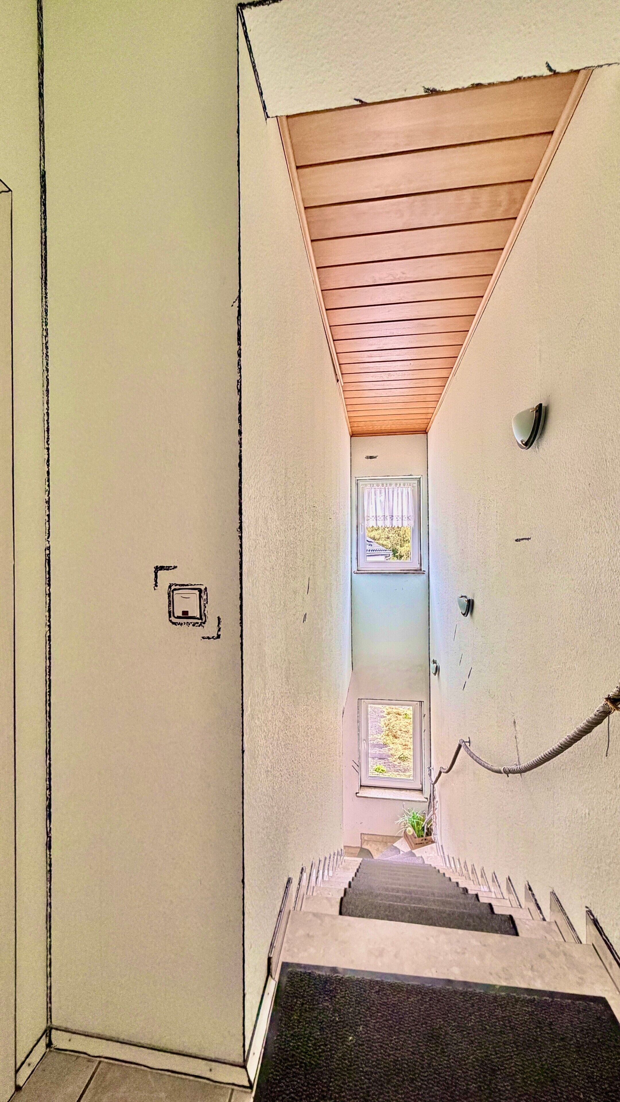 Una escalera estrecha que conduce a una plataforma con techo de madera y una ventana pequeña con vistas a un jardín.