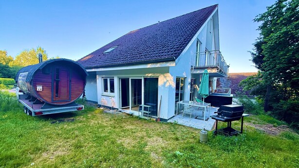 Ein Haus mit einem großen Fass, einem Balkon und einer Terrasse.
