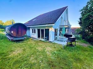 Ein Haus mit einem großen Fass, einem Balkon und einer Terrasse.