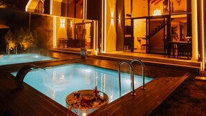 Un hotel moderno con piscina, amplias ventanas de vidrio y una terraza de madera.