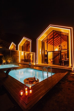 A modern hotel with a swimming pool, large glass windows, and a wooden deck.