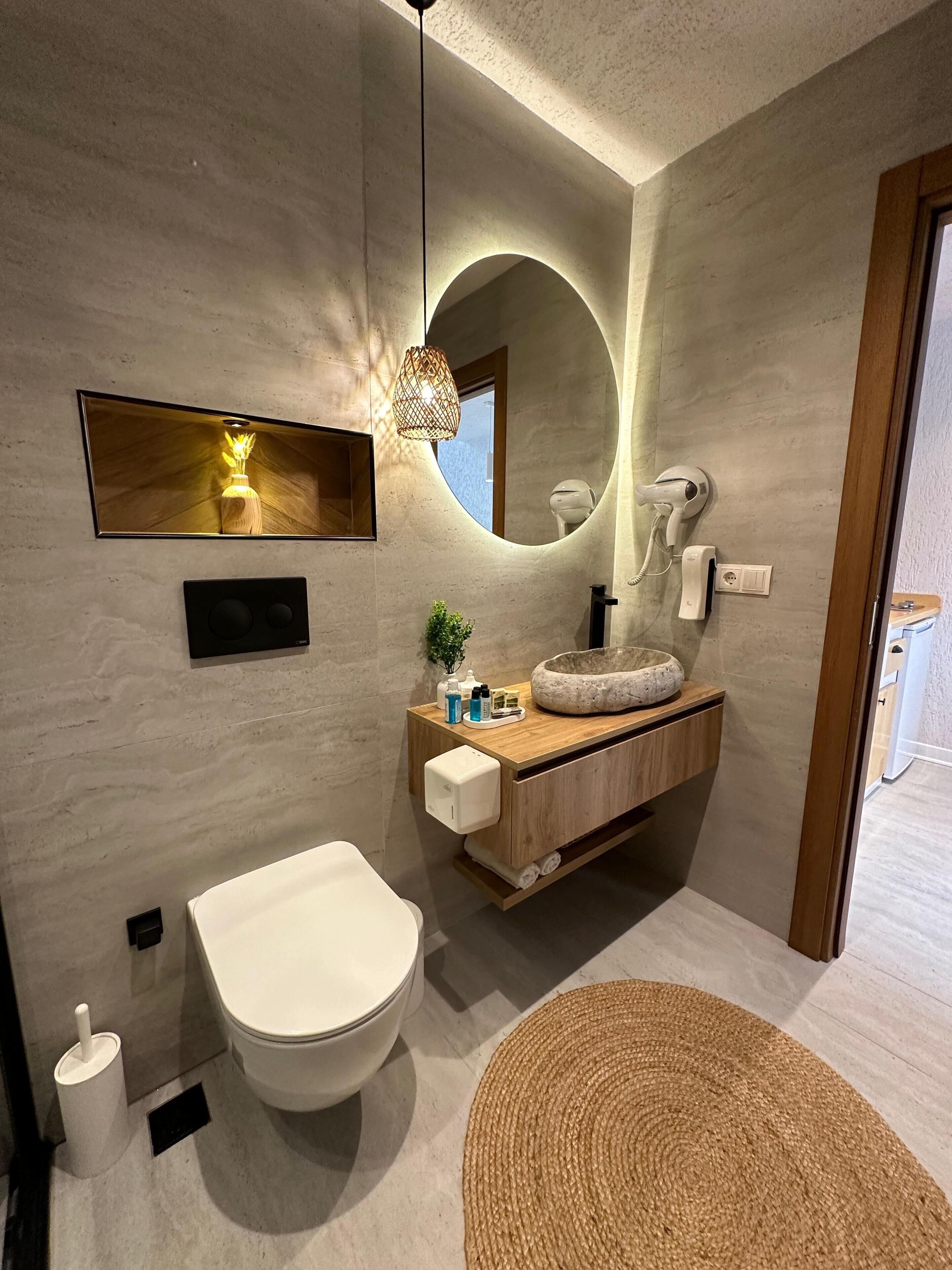 A modern bathroom with a toilet, sink, and mirror.