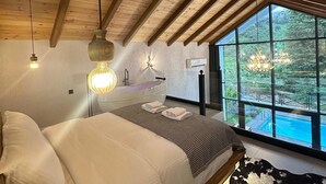 Un dormitorio con una cama grande, vistas a una piscina y techo de madera.