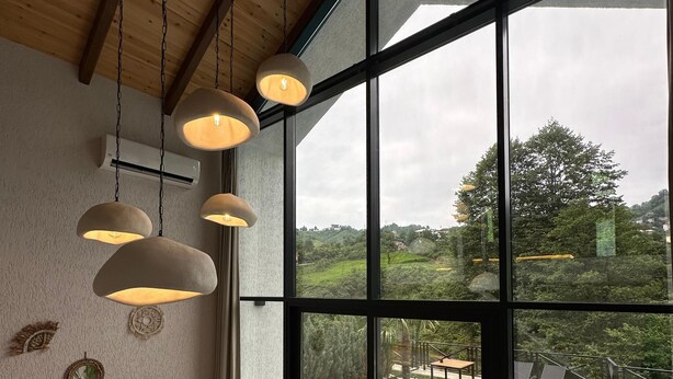 Un interior moderno con un ventanal grande, un sofá gris, lámparas colgantes y una mesa de centro de madera.
