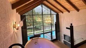Una habitación con un ventanal grande, una bañera y techo de madera.