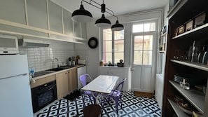Een kleine keuken met een eettafel, stoelen en een raam met uitzicht.