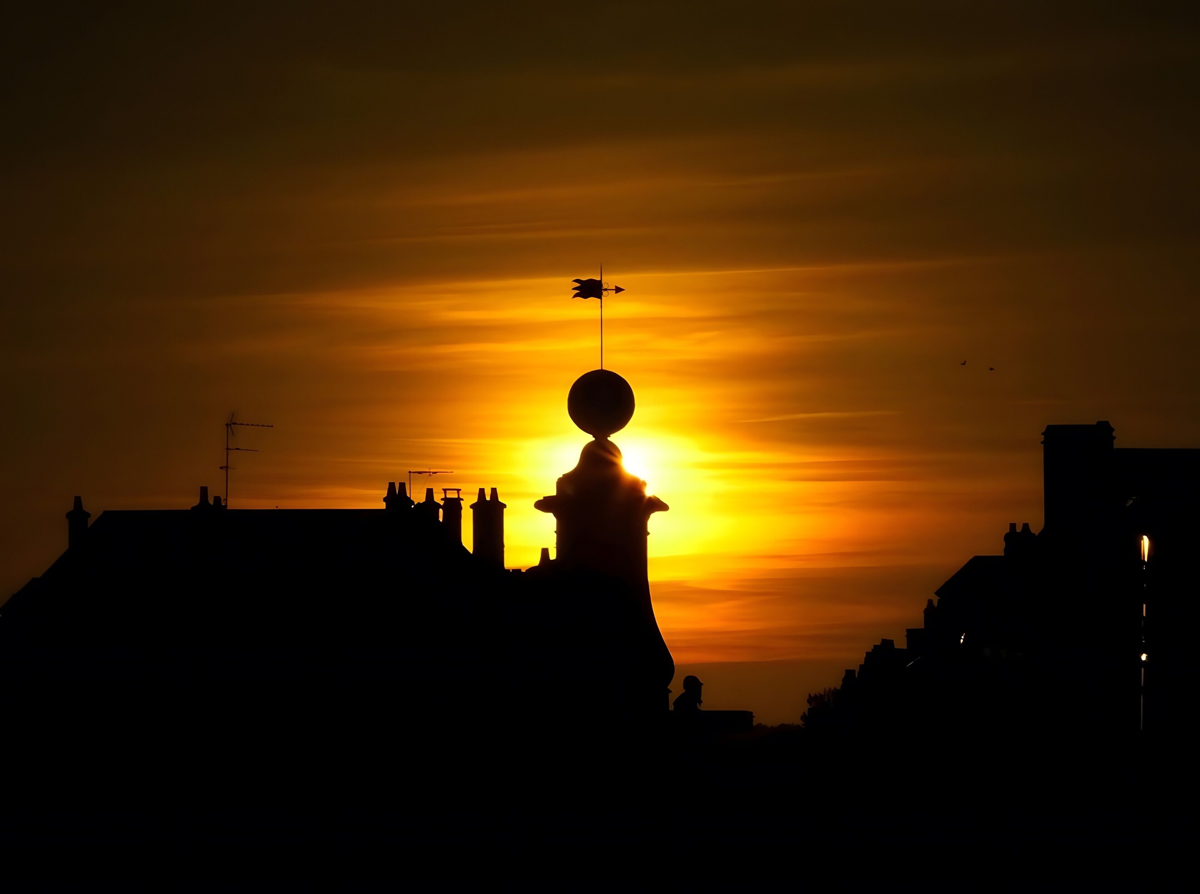 A silhouette of a building with a prominent tower against a sunset sky.