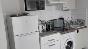 A modern kitchen with a refrigerator, microwave, coffee maker, and washing machine.