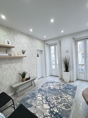 Un interior moderno con una pared de mármol, un banco, una planta en maceta y una alfombra estampada.