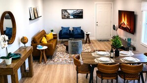 Ein modernes Wohnzimmer mit Sofa, Couchtisch, Esstisch, Stühlen und einem Kamin.