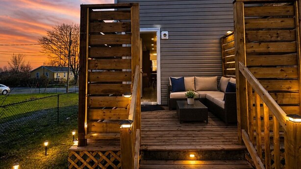 Ein Haus mit Terrasse, Sitzgelegenheiten im Freien und einem umzäunten Garten.