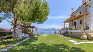 A house with a stone facade, a wooden pergola, and a view of the sea.