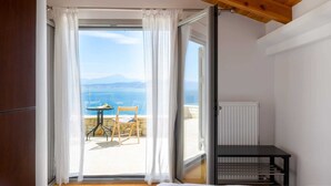 A bedroom with a view of the sea, a small table with a chair, and a radiator.