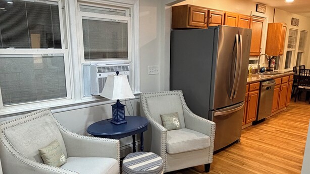 A modern kitchen with a refrigerator, stove, and wooden cabinets. There is a seating area with two chairs and a small table. - Shore House, Beach + Boardwalk, Parking for 7, Point Pleasant Beach (Point Pleasant Beach)