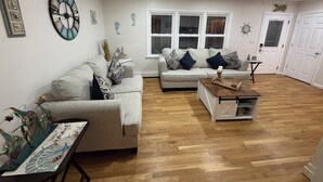 A living room with a sofa, a coffee table, decorative wall art, and a ceiling fan. - Shore House, Beach + Boardwalk, Parking for 7, Point Pleasant Beach (Point Pleasant Beach)