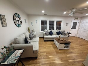 Ein Wohnzimmer mit einer Couch, einem Couchtisch, Wandbildern und einem Deckenventilator.
