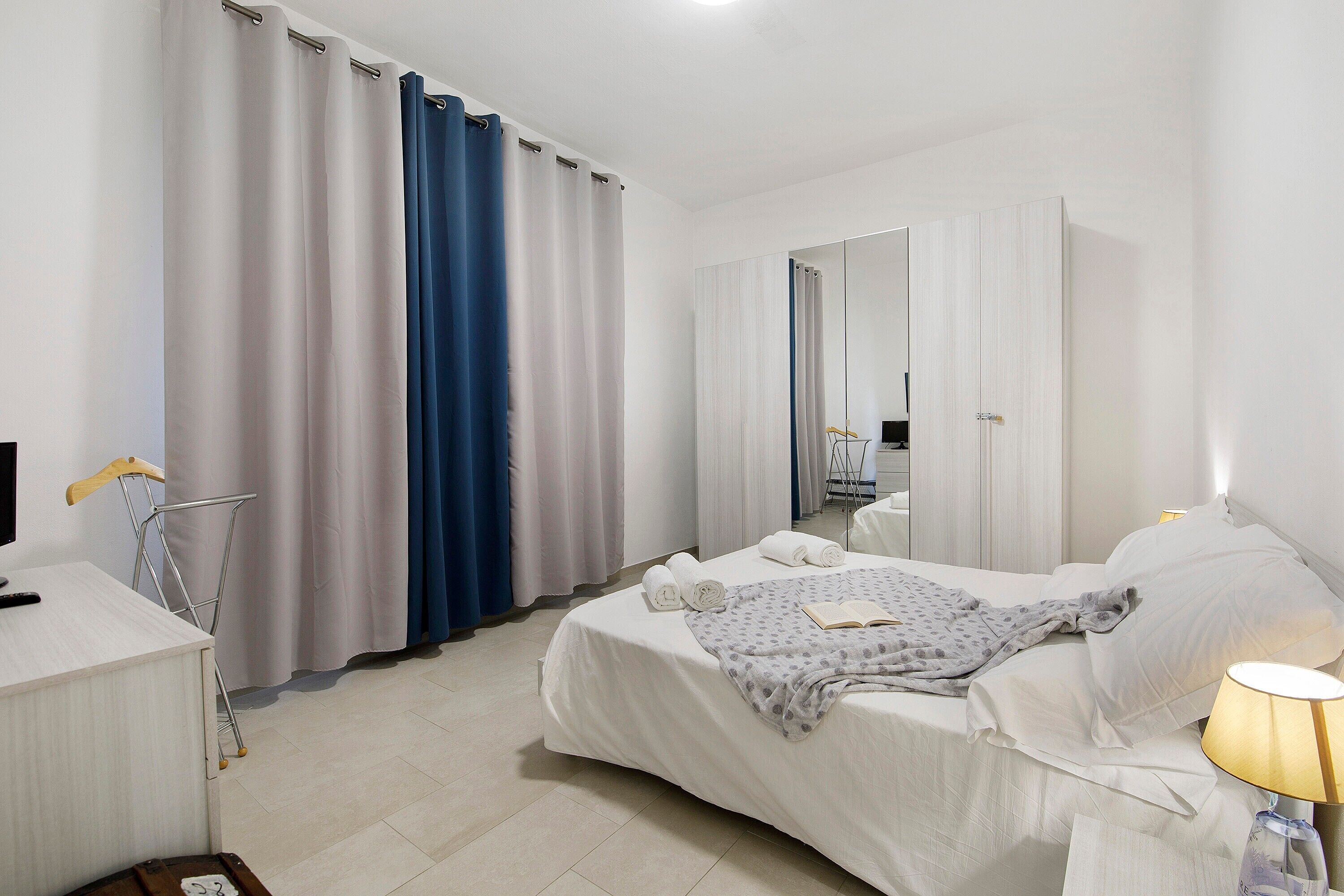 Una habitación de hotel con una cama, un escritorio, una silla, una lámpara y un espejo.