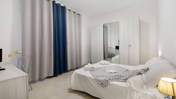 Una habitación de hotel con una cama, un escritorio, una silla, una lámpara y un espejo.