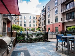 A courtyard with a grill, outdoor seating, and a pool.