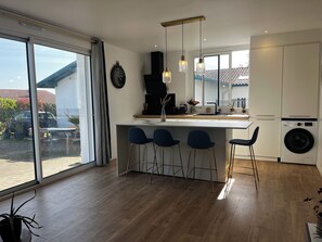 Eine moderne Küche mit einem großen Fenster, Barhocker, einer Waschmaschine und einer Wanduhr.