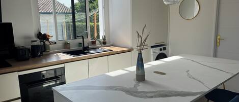 Une cuisine moderne dotée d’un îlot central, d’un four Bosch, d’un évier et d’un lave-linge.