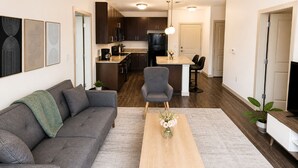 Een moderne woonkamer met een bank, salontafel en een eethoek met stoelen.