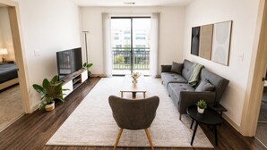 Een woonkamer met een bank, een televisie, een salontafel en een plant.