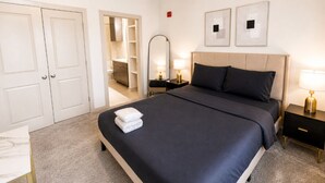 Een hotelkamer met een bed, nachtkastjes, een spiegel, een kledingkast en een klein bureau met een stoel.