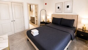 Ein Hotelzimmer mit einem Bett, Nachttischen, einem Spiegel, einem Kleiderschrank und einem kleinen Schreibtisch mit Stuhl.