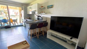 A modern kitchen with a large TV, bar stools, and a dining area with a view. - REF DOLOS BY PALMES D OR PROPERTIES (Cannes)