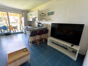 A modern kitchen with a large TV, bar stools, and a dining area with a view. - REF DOLOS BY PALMES D OR PROPERTIES (Cannes)