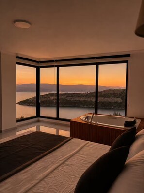 Ein modernes Schlafzimmer mit großem Fenster, einer Badewanne und einem Bett.