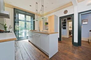 Eine moderne Küche mit einer großen Kochinsel, Holzböden und Blick durch eine Glastür.
