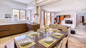 A modern kitchen with a dining area, a TV, and a sofa.