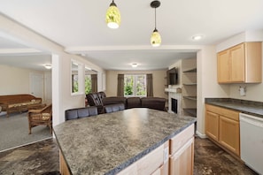 A spacious kitchen with a granite countertop, wooden cabinets, and pendant lighting.