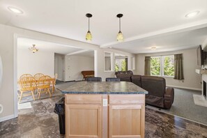 A spacious living area with a kitchen island, seating, and a fireplace.