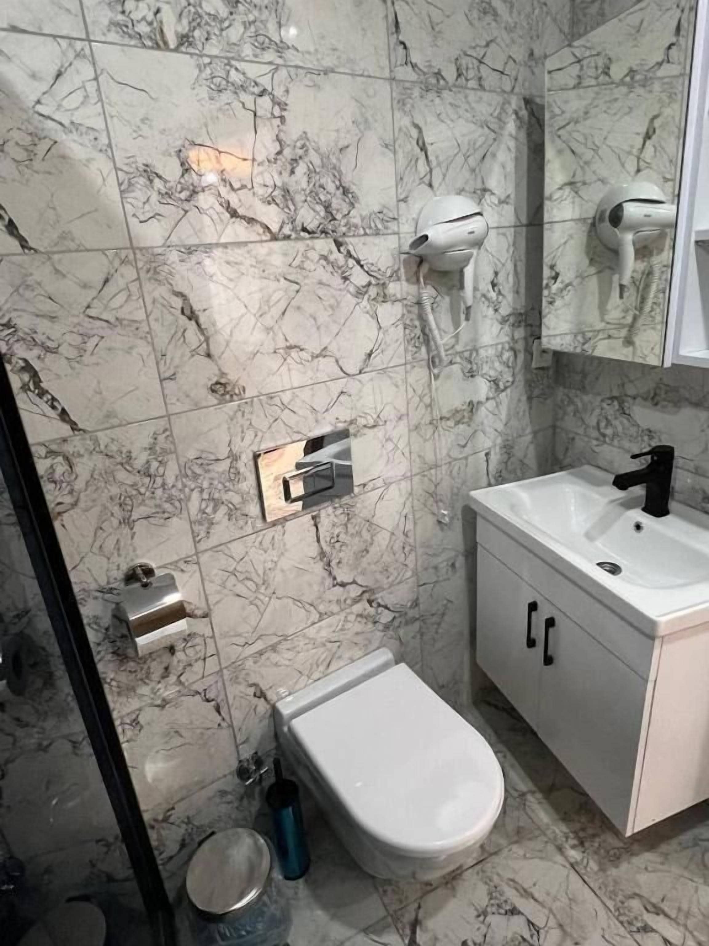 Ein Badezimmer mit Marmorwänden, einem weißen Waschbecken, einem Bidet und einem Handtuchhalter.