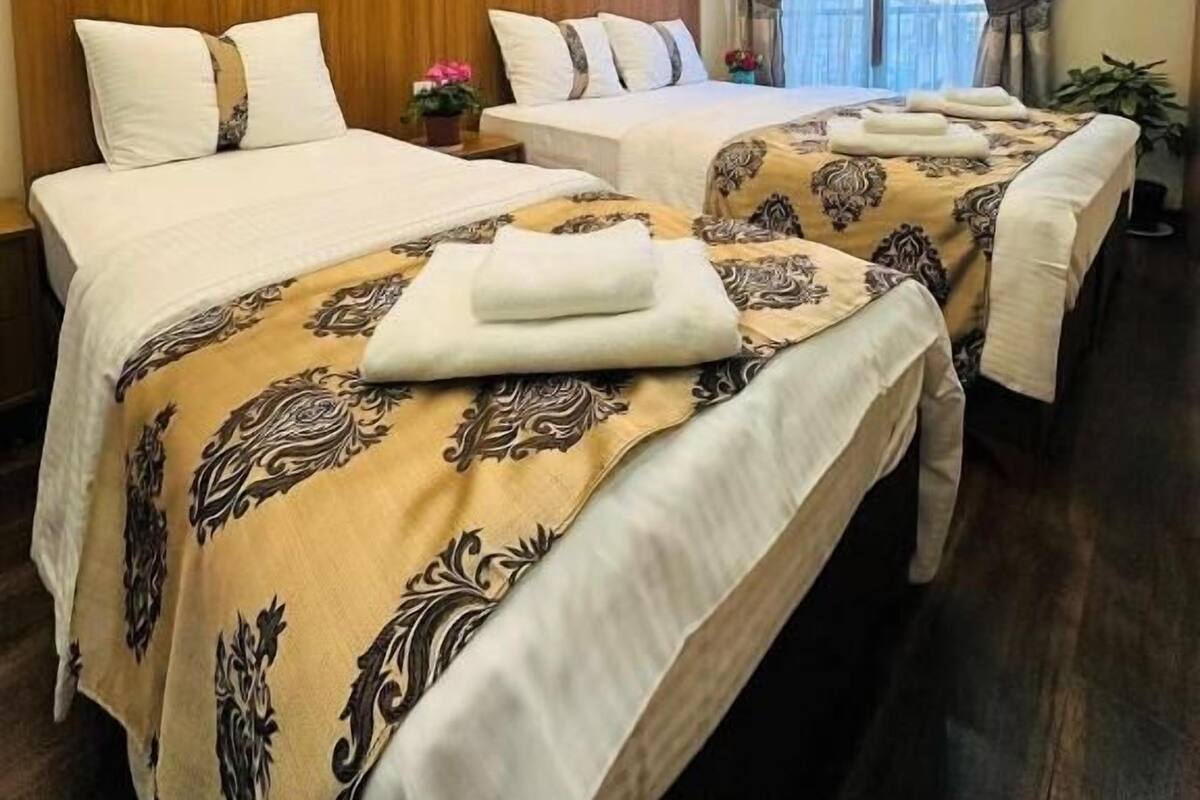 Quarto de hotel com duas camas, um quadro na parede e uma janela com cortinas.