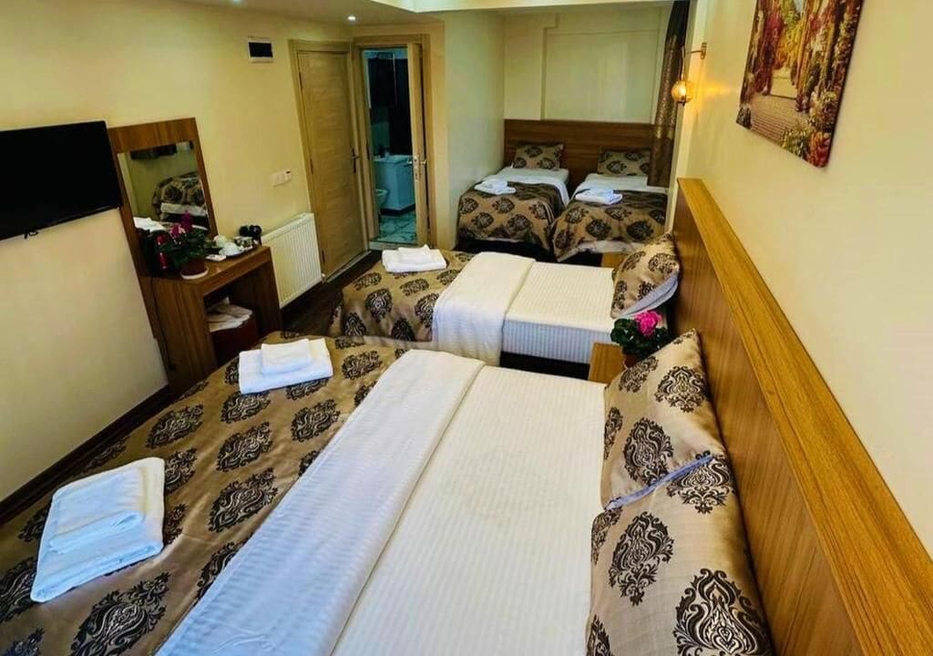 Une chambre d’hôtel avec deux lits, une télévision, un miroir, un bureau et une porte de salle de bain.