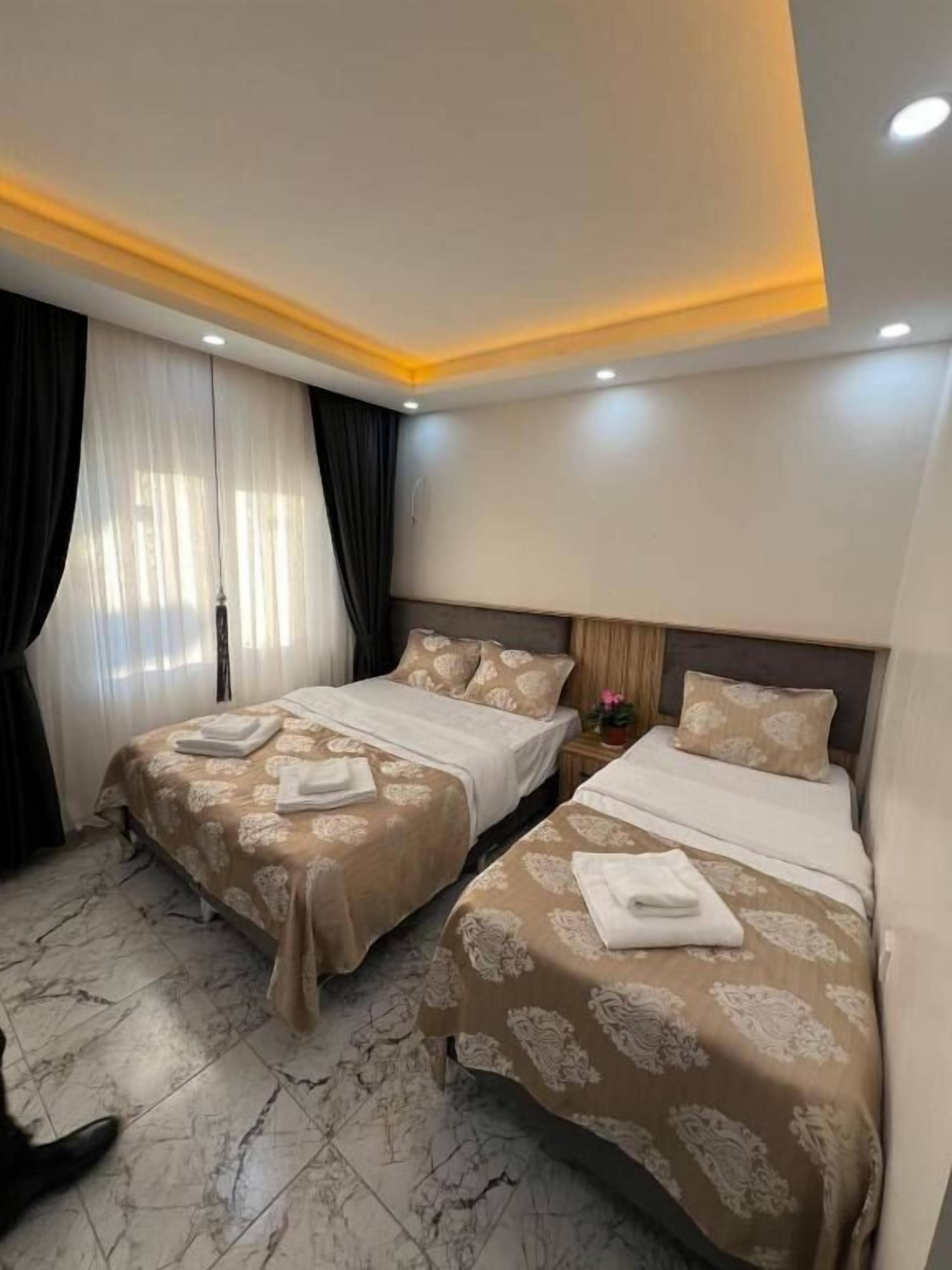 A hotel room with two beds, a marble floor, and a modern ceiling design.