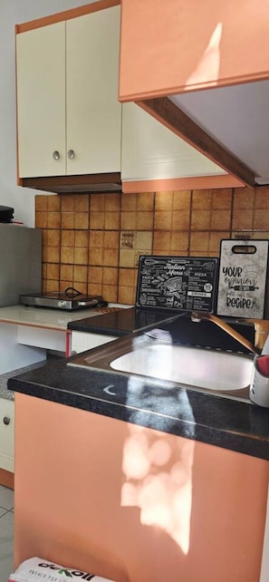 Eine Küche mit schwarzer Arbeitsplatte, einem weißen Schrank und einer gefliesten Rückwand.