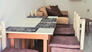 En matplats med ett långt bord, bekväma stolar, en tv som är monterad på väggen och en soffa i bakgrunden.