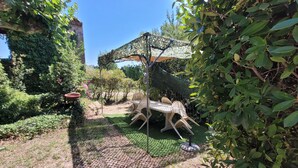 En trädgård med ett bord och stolar, en pergola och olika växter.