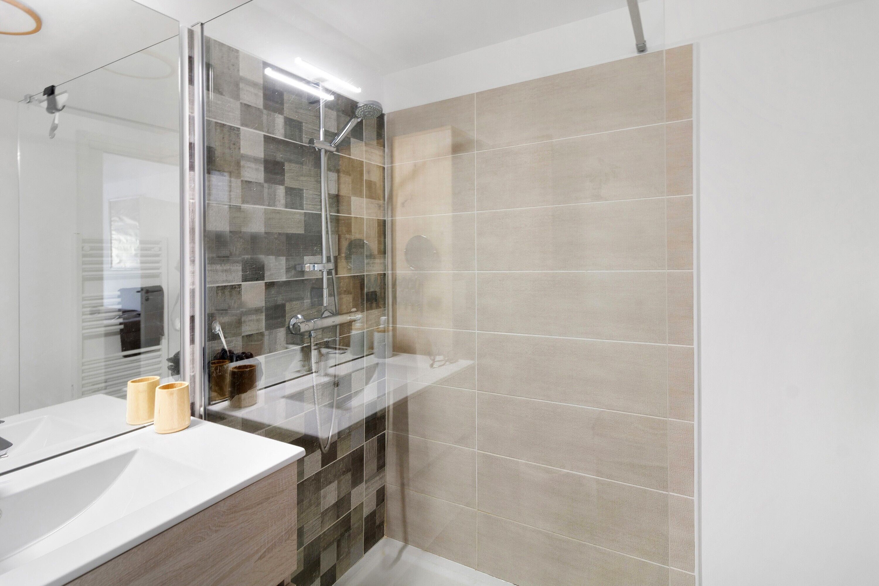 A modern bathroom with a glass shower enclosure, a white sink, and a mirror.