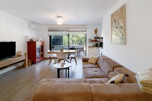 Ein Wohnzimmer mit Sofa, Fernseher und Essbereich.
