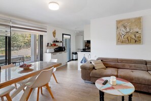 Ein modernes Wohnzimmer mit Essbereich, einer Couch und einem Gemälde an der Wand.