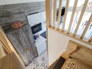 A kitchen with a microwave, cabinets, and a wooden floor. - Posh Pod (Cemaes Bay)