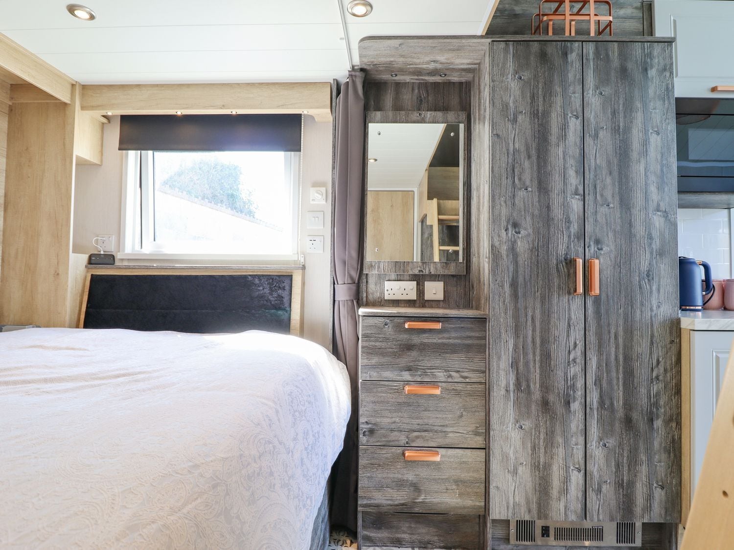 Un dormitorio con cama, ventana, armario y espejo.