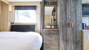 Un dormitorio con cama, ventana, armario y espejo.