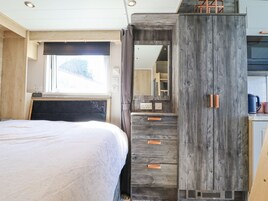 Un dormitorio con cama, ventana, armario y espejo.